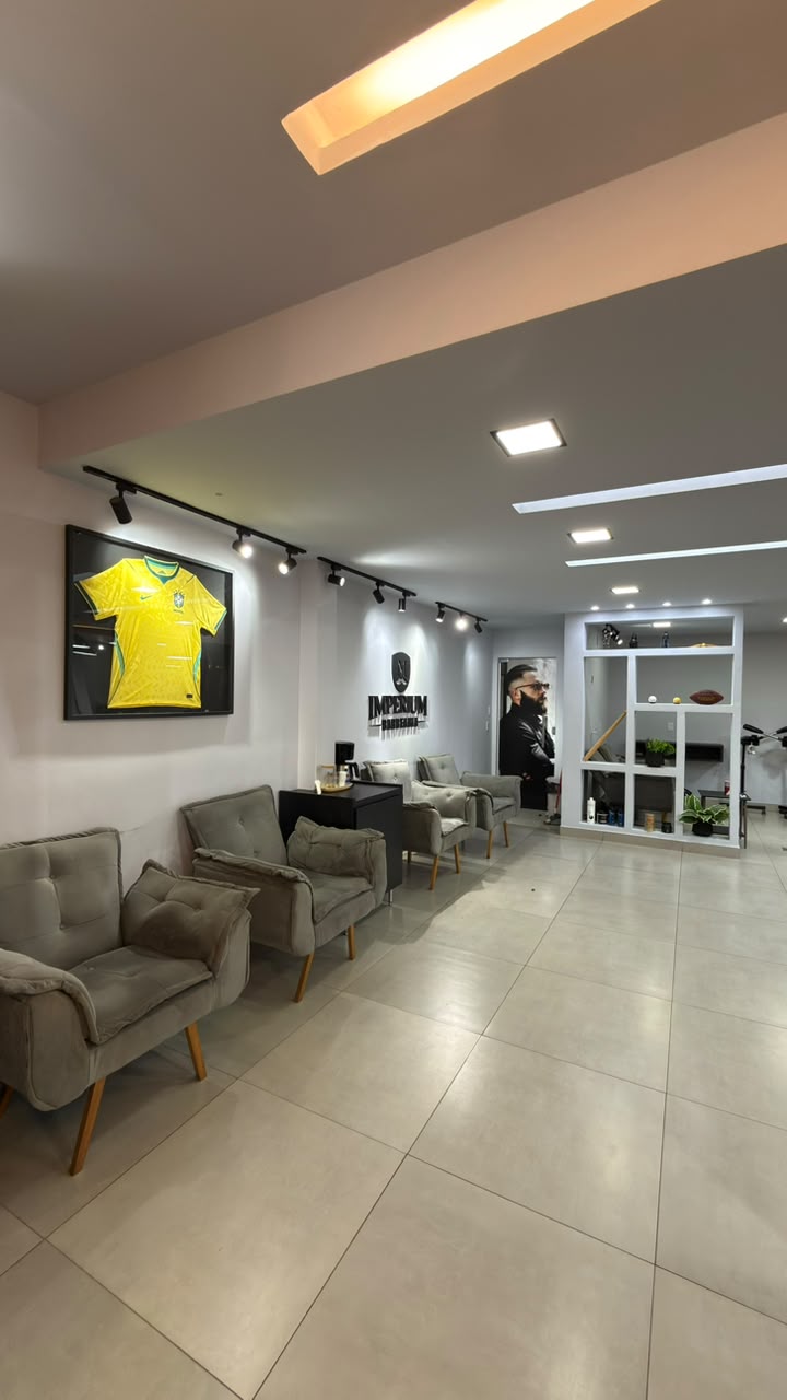 Sala de espera da Barbearia Imperium M com poltronas e painel da marca
