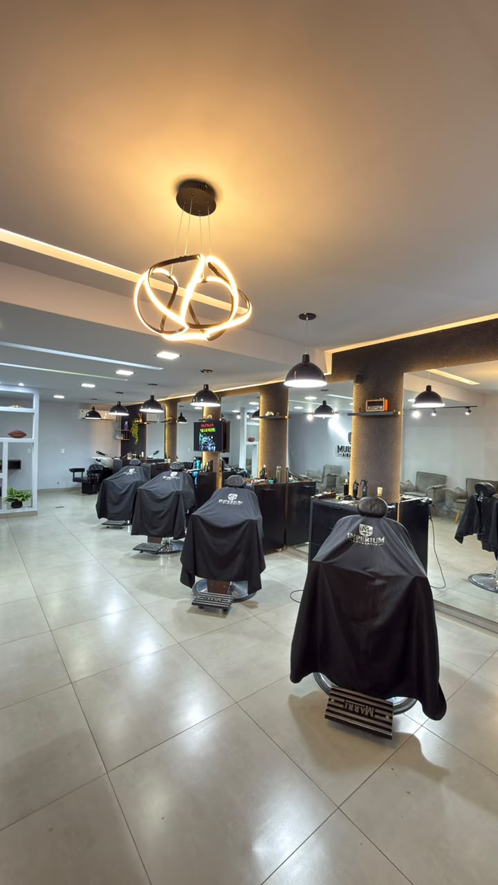Estações de corte da Barbearia Imperium M sob iluminação quente